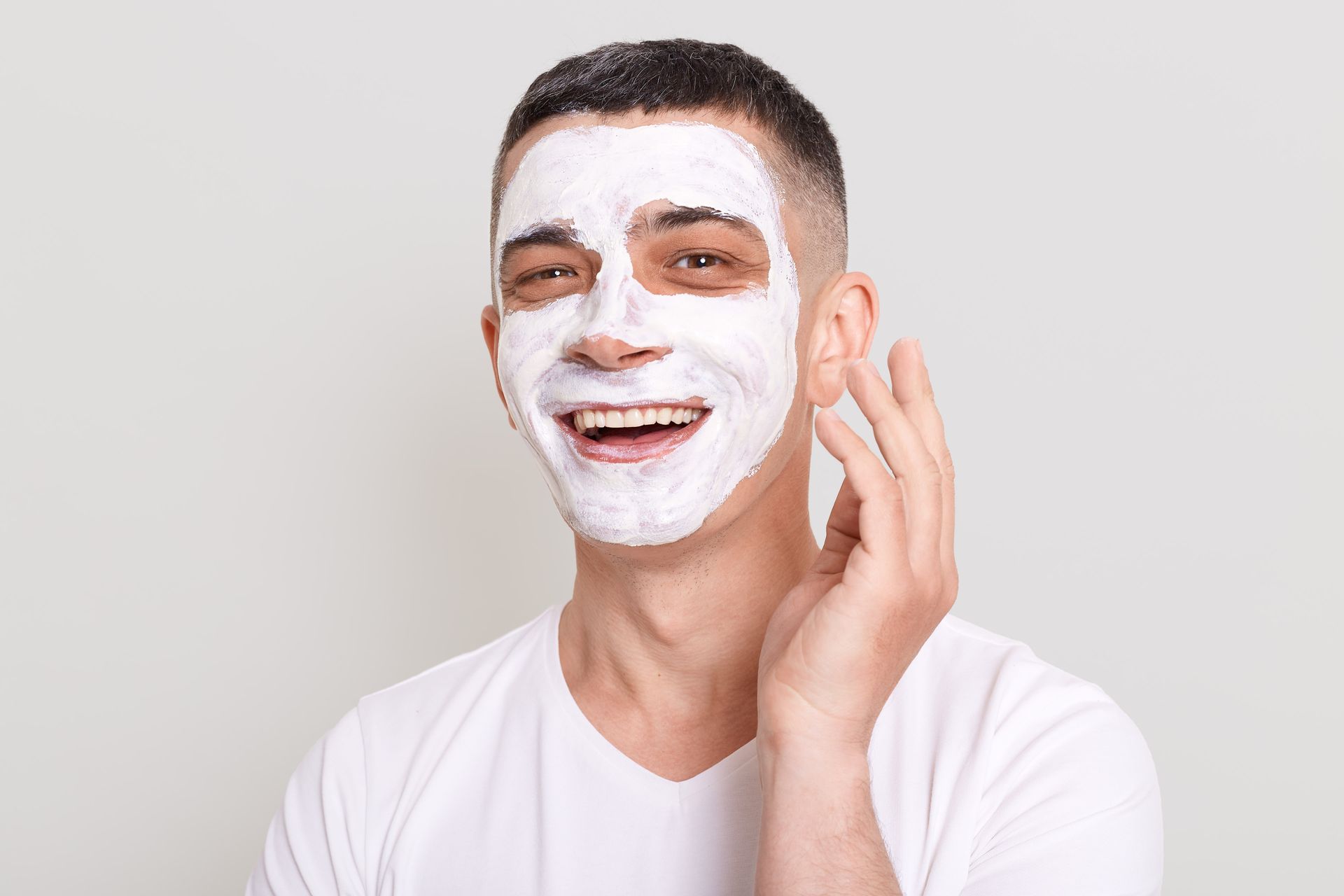 A woman is smiling and touching her face with her hands.