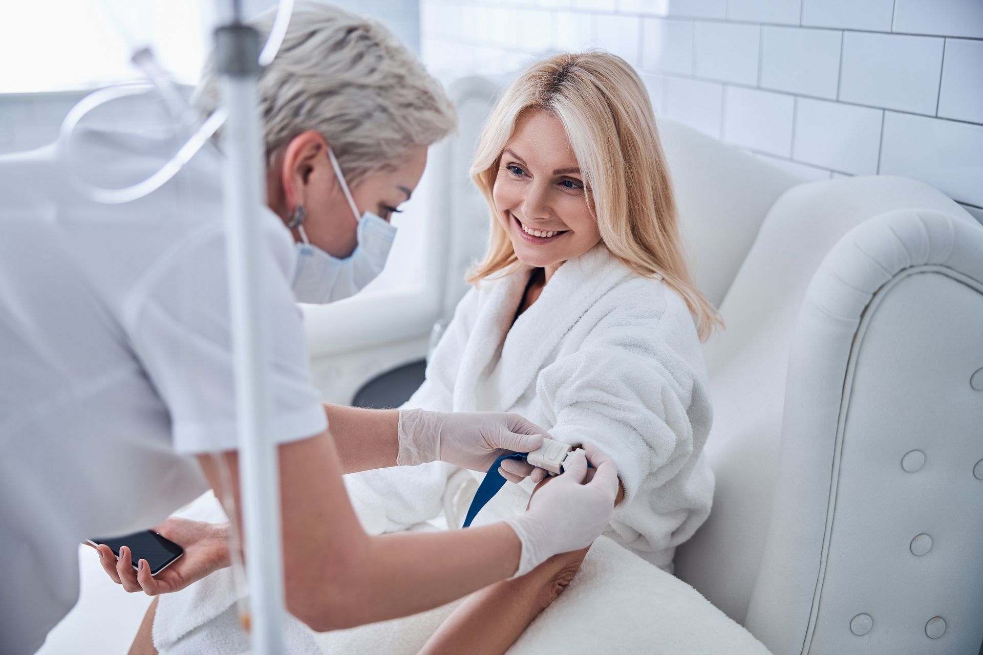 A woman is sitting on a couch getting an injection from a nurse.