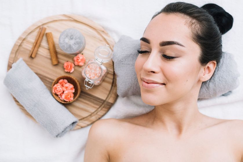 A woman is laying on a bed in a spa with her eyes closed.