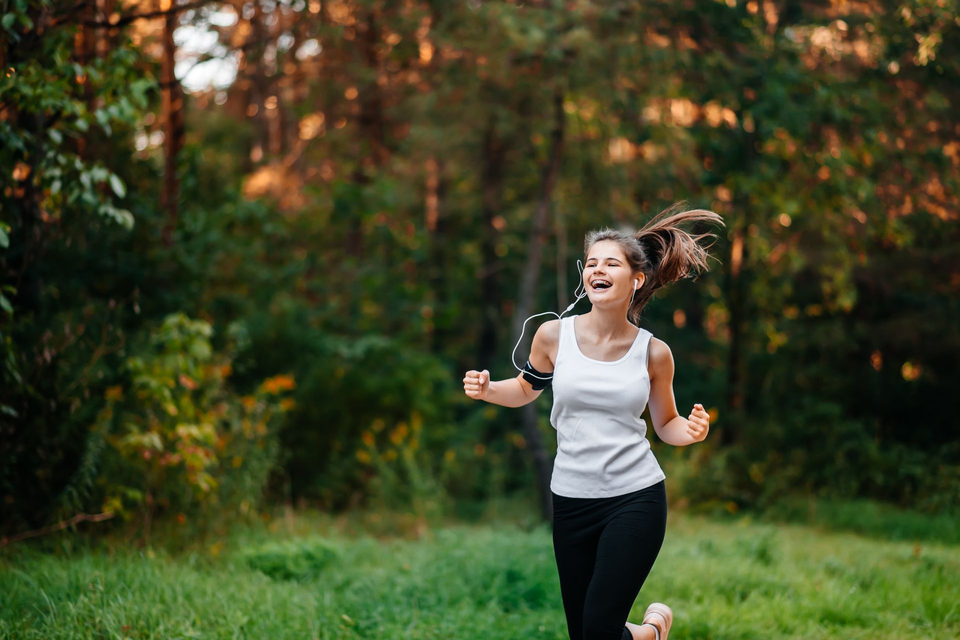 A young woman is running in the woods.