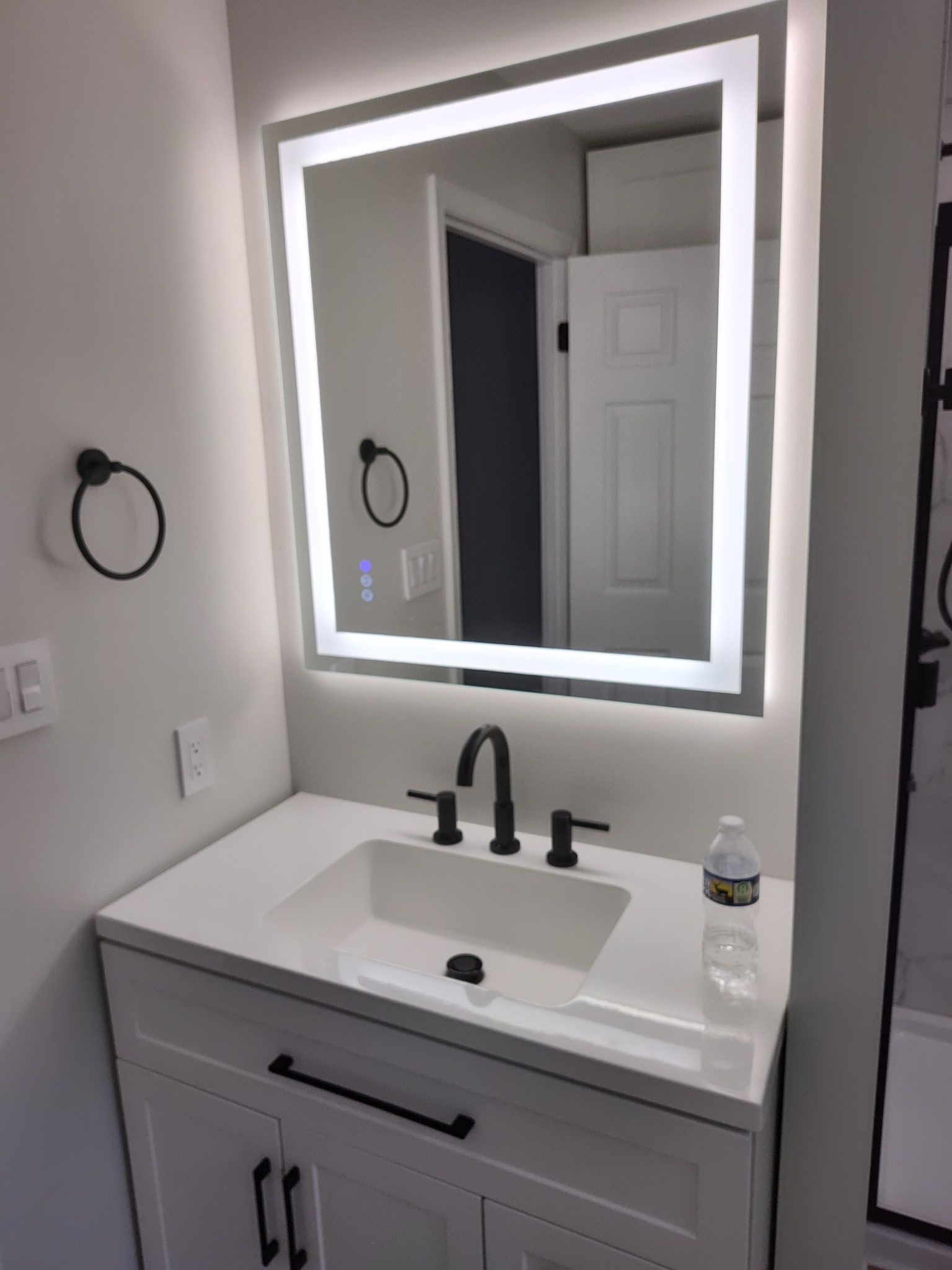 A bathroom sink with a lighted mirror above it