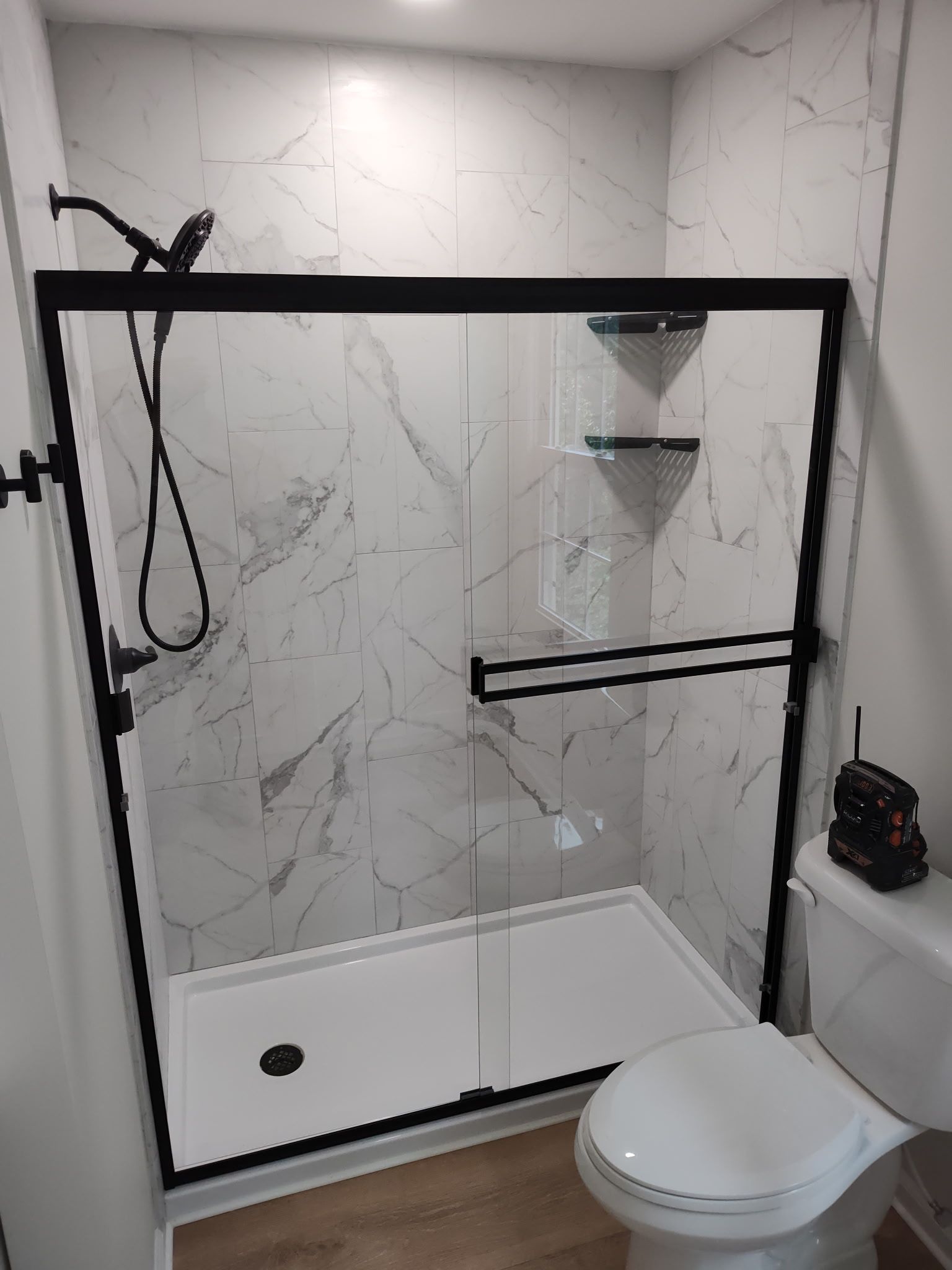 A bathroom with a toilet and a shower with a black frame.