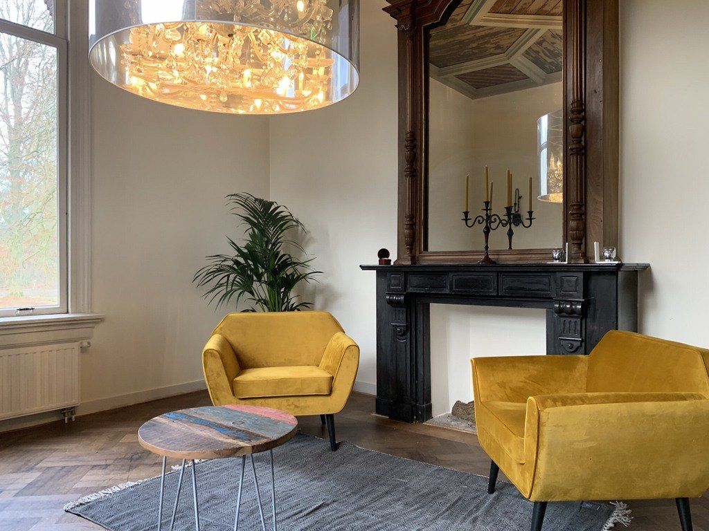 Een woonkamer met twee gele stoelen en een open haard.