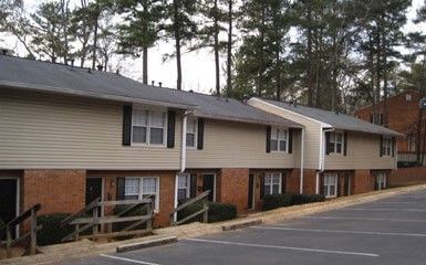 a row of apartment buildings with a parking lot in front