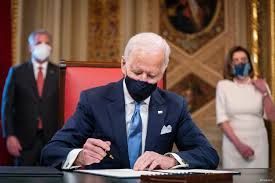 a man in a suit and tie is signing a document while wearing a mask