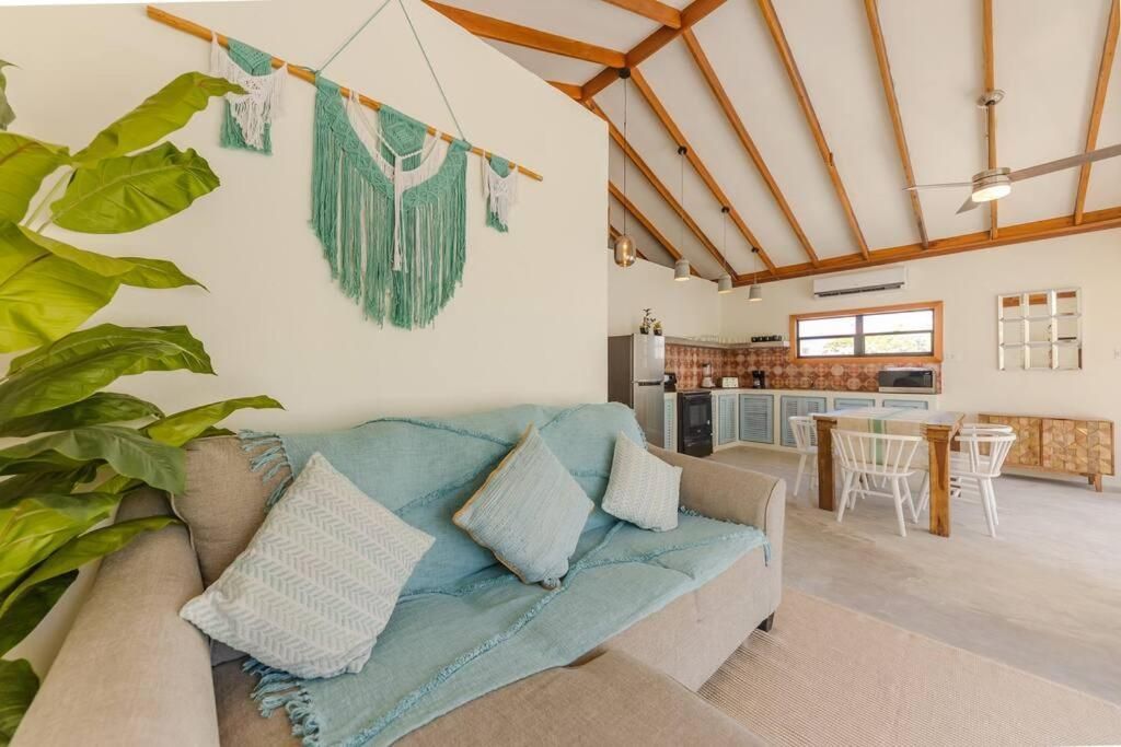 Cozy living room with a sofa, macrame wall hanging, and kitchen area in an open layout.