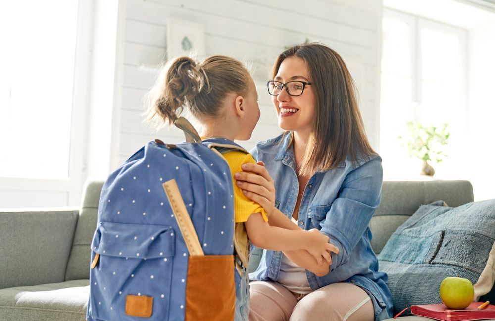 A Woman is Sitting on a Couch Holding a Little Girl With a Backpack — Woodlands Child Care Centre in East Albury, NSW