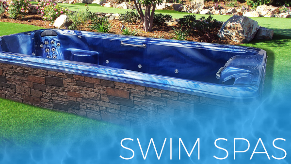 Blue in-ground swim spa with stone exterior in a landscaped backyard