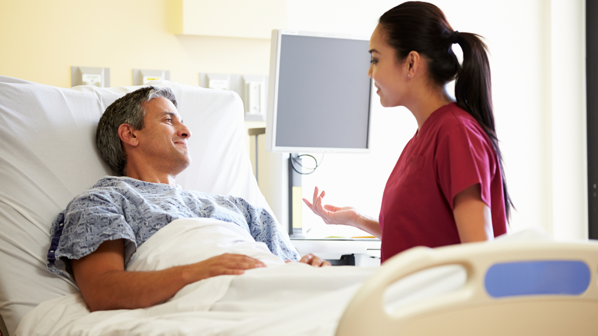 Nurse talking to a patient in a hospital bed.