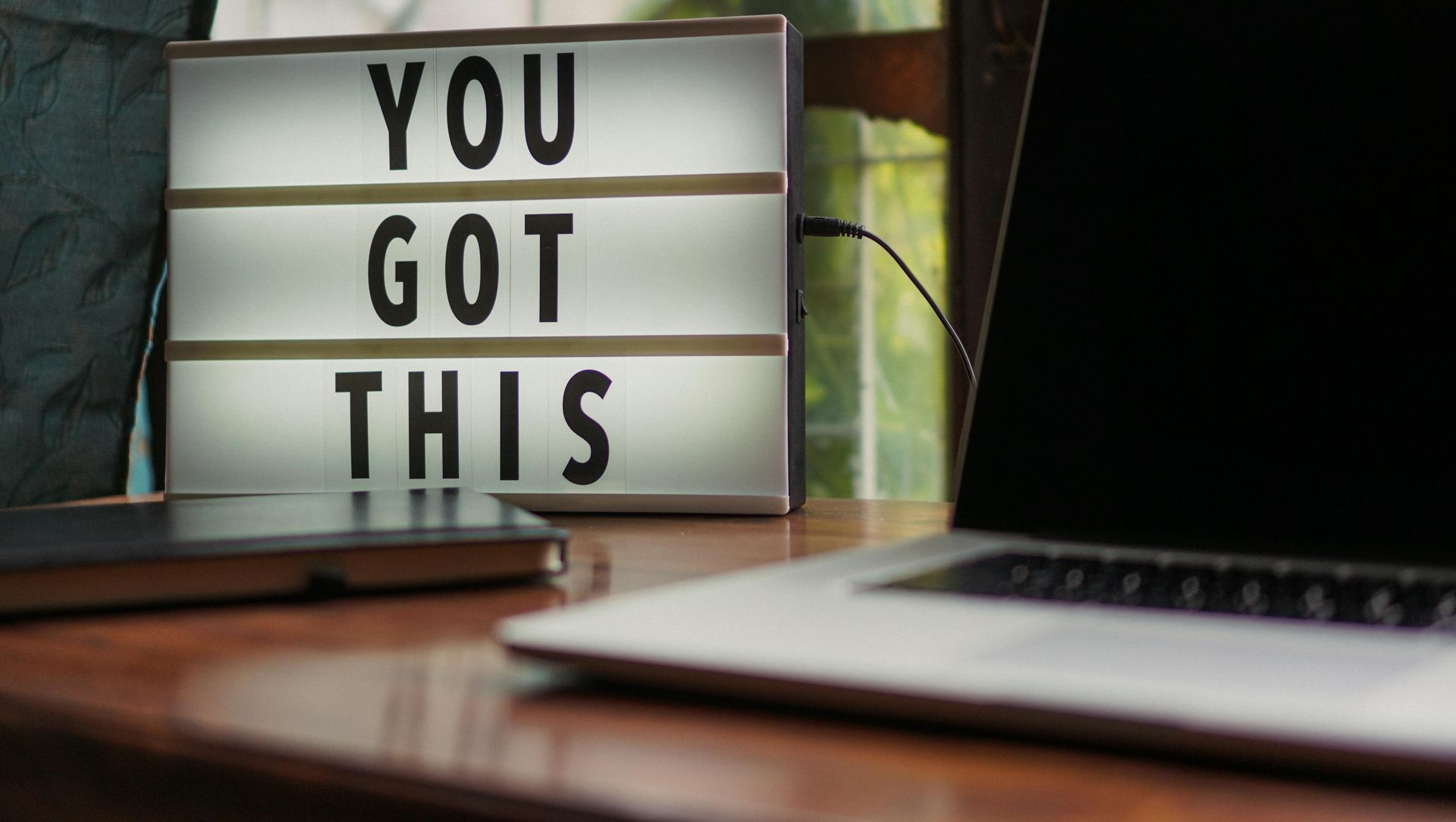 A light box on a desk displays the words