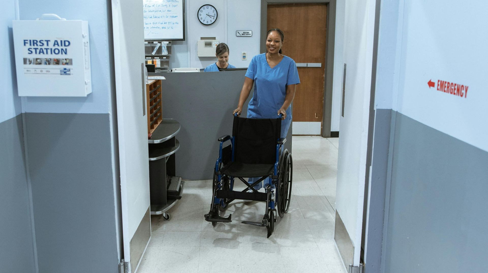 Nurse pushing a wheelchair through a hospital hallway.
