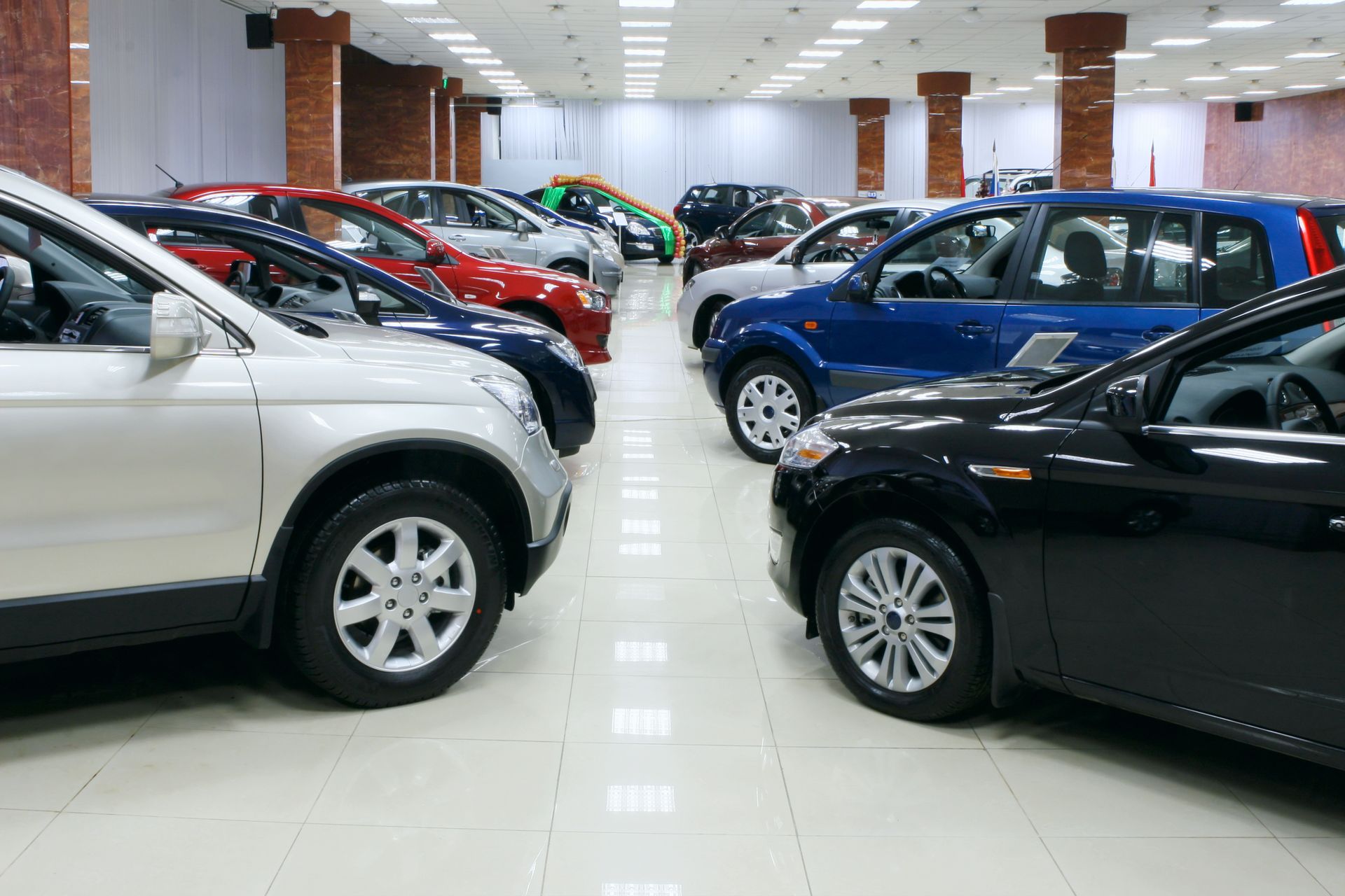 A lot of cars are parked in a showroom.