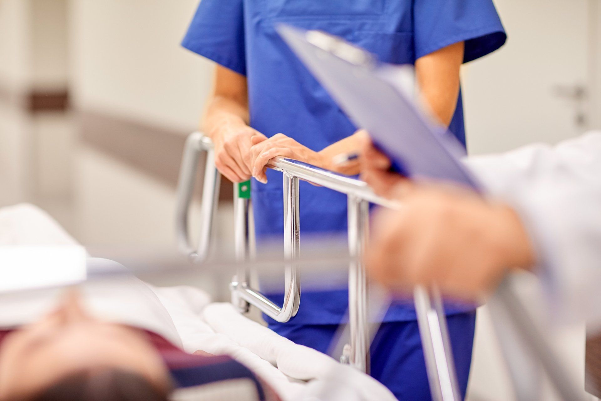 Nurse standing by a doctor holding a note pad at the side of medical bed