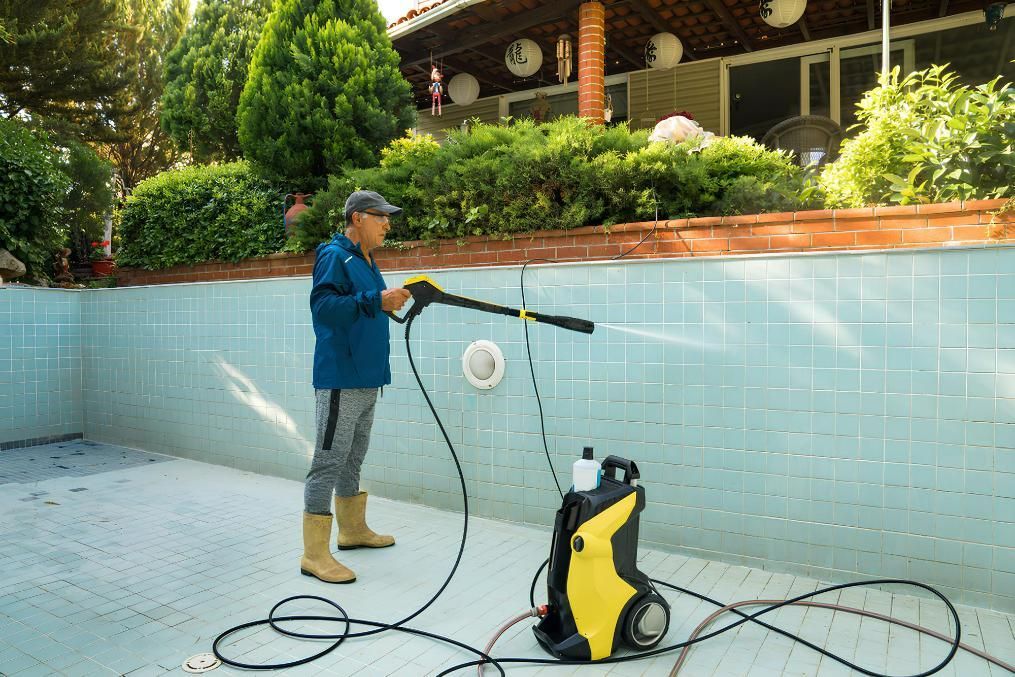 A Man Is Using a High Pressure Washer to Clean a Swimming Pool — Tweed Coast Pool Care in South Murwillumbah, NSW