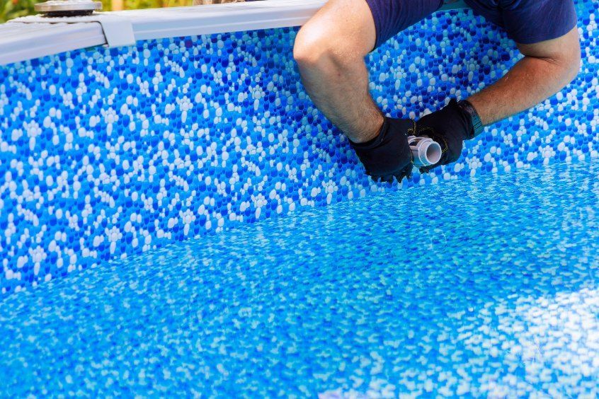A Man is Working on the Side of a Swimming Pool — Tweed Coast Pool Care in Numinbah, NSW