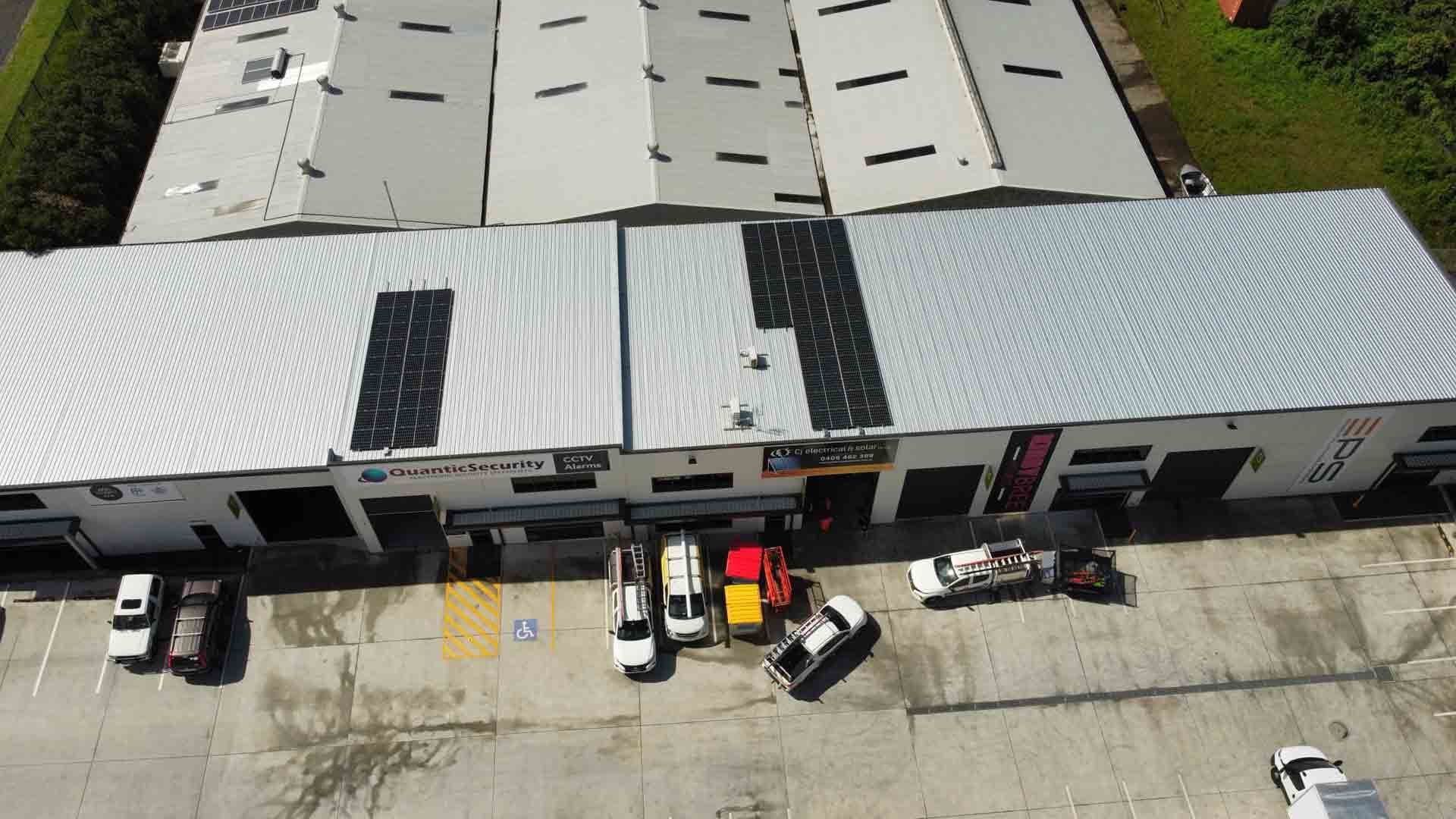 An Aerial View Of A Warehouse With Cars Parked In Front Of It — CJ Electrical & Solar In Broadmeadow, NSW