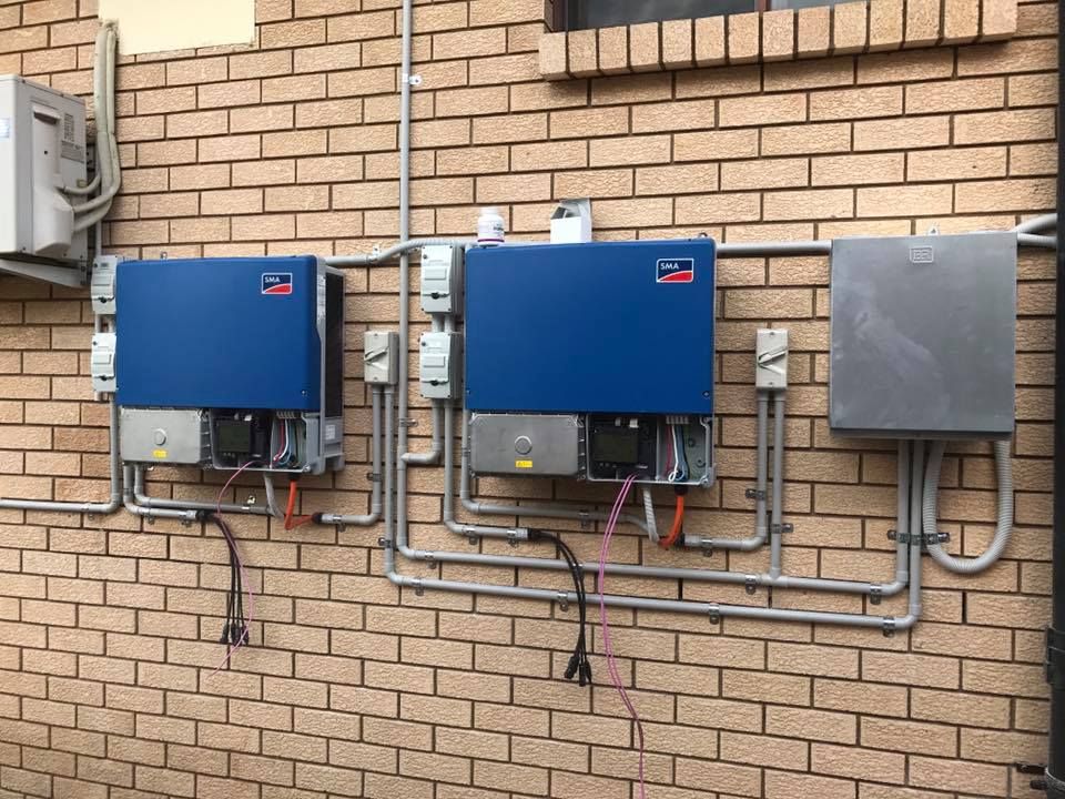 A Row Of Blue Solar Panels Mounted On A Brick Wall — CJ Electrical & Solar In Blue Haven, NSW