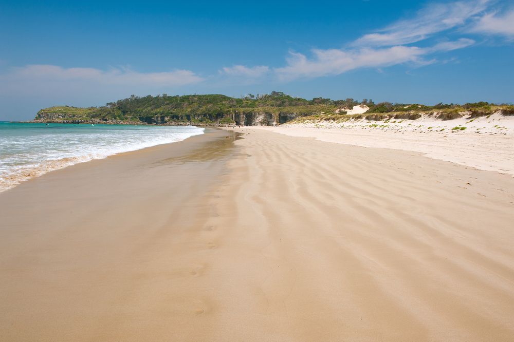 A Sandy Beach With Waves Coming In On A Sunny Day — CJ Electrical & Solar In Swansea, NSW