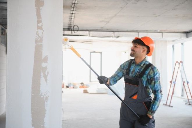 A man is painting a wall with a paint roller.