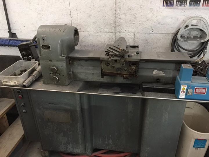 A lathe is sitting on top of a table in a garage.