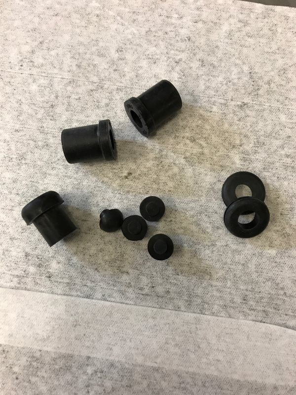 A bunch of black rubber nuts and washers are sitting on a piece of paper.