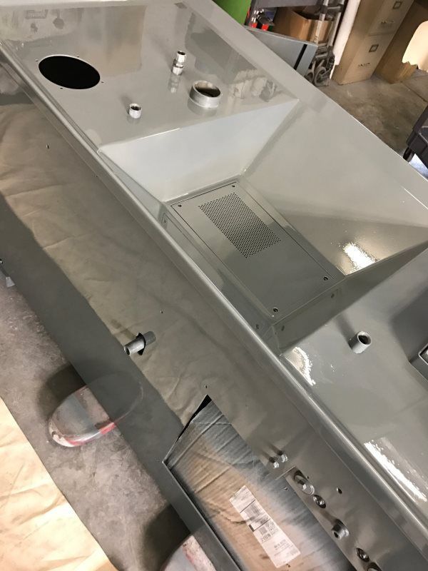 A stainless steel sink is sitting on the floor in a room.