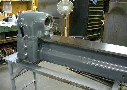 A lathe is sitting on a table in a garage next to a fan.