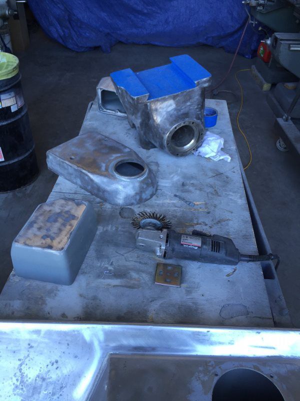 A table with a lot of pieces of metal on it and a grinder on it.