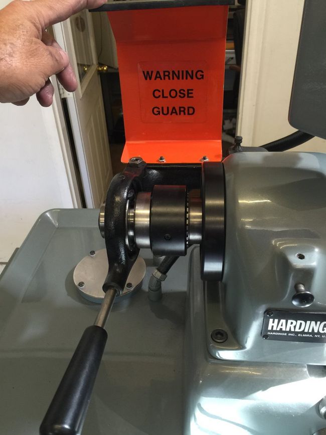 A person is holding a warning close guard on a machine.