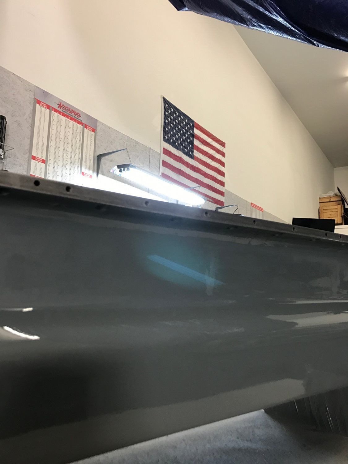 A pool table with an american flag on the wall behind it