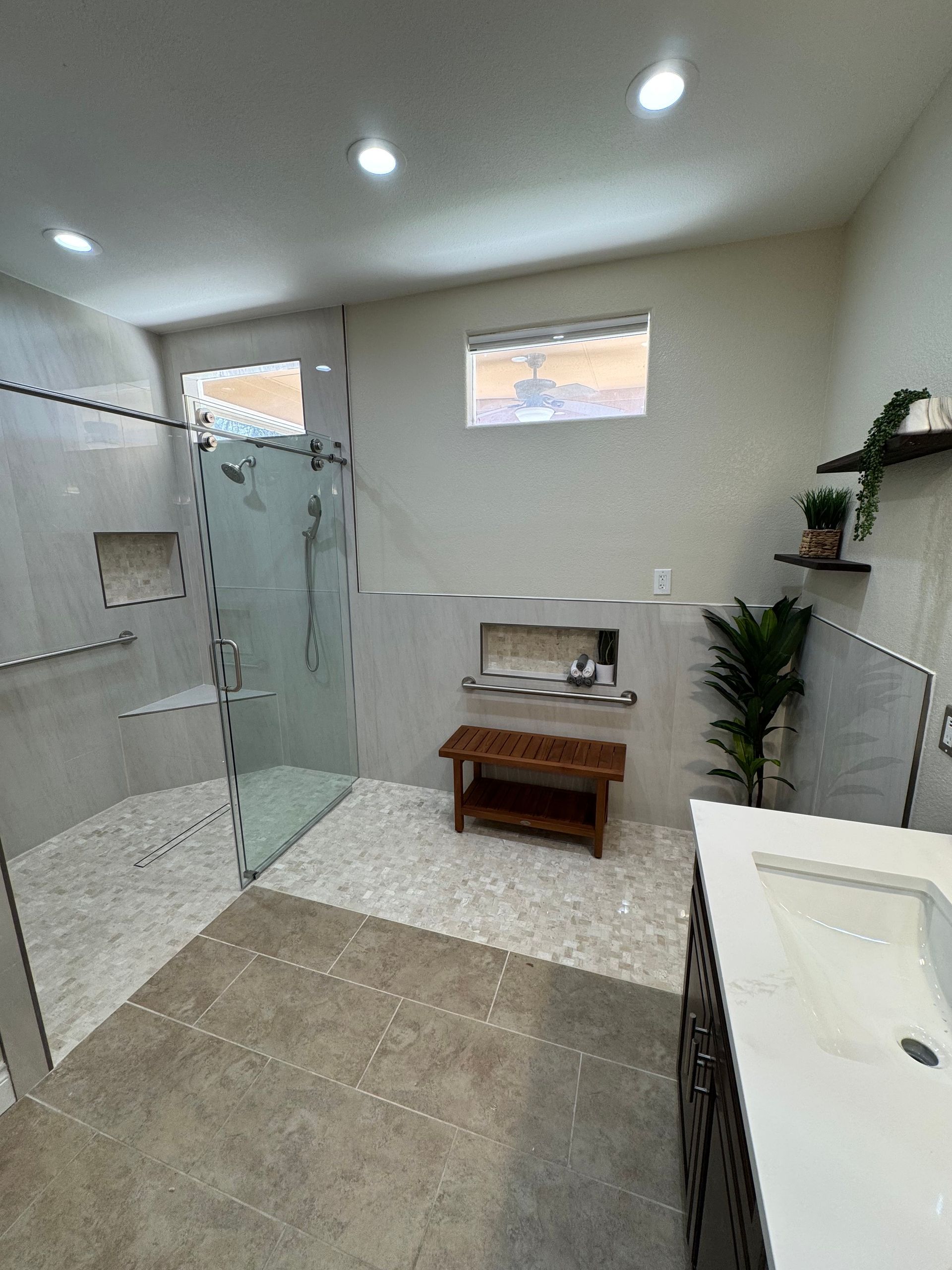 A bathroom with a walk in shower , sink , and window.