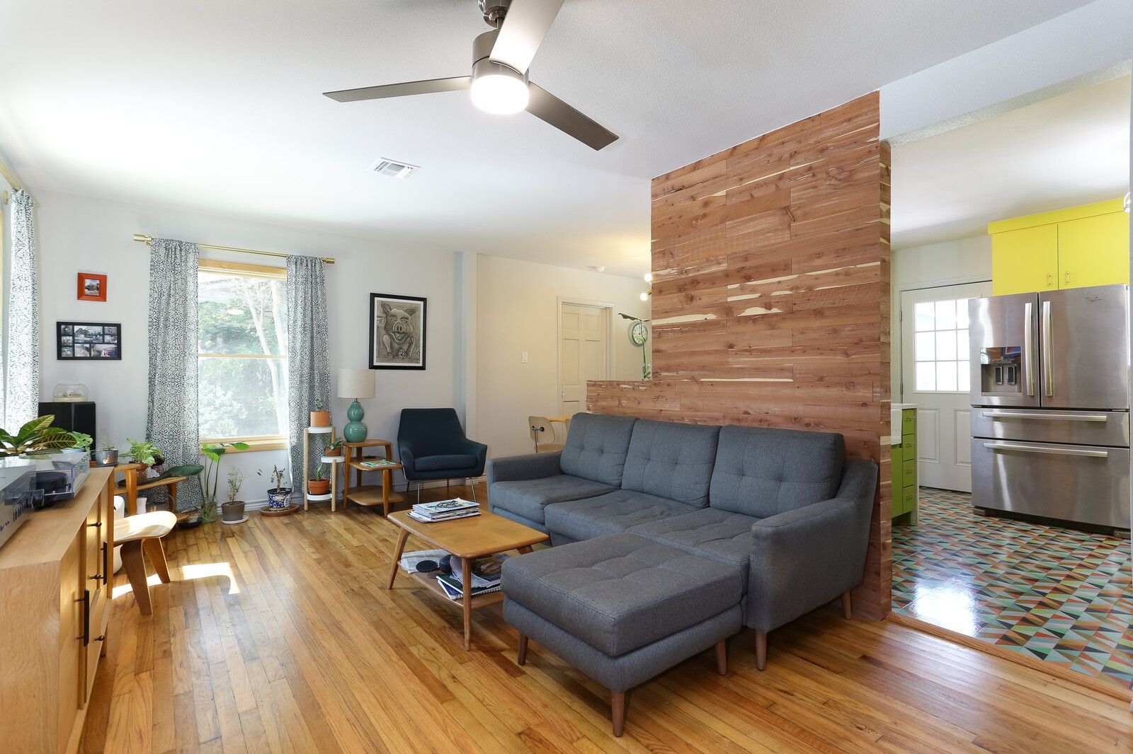 A living room with a sectional couch and a ceiling fan.