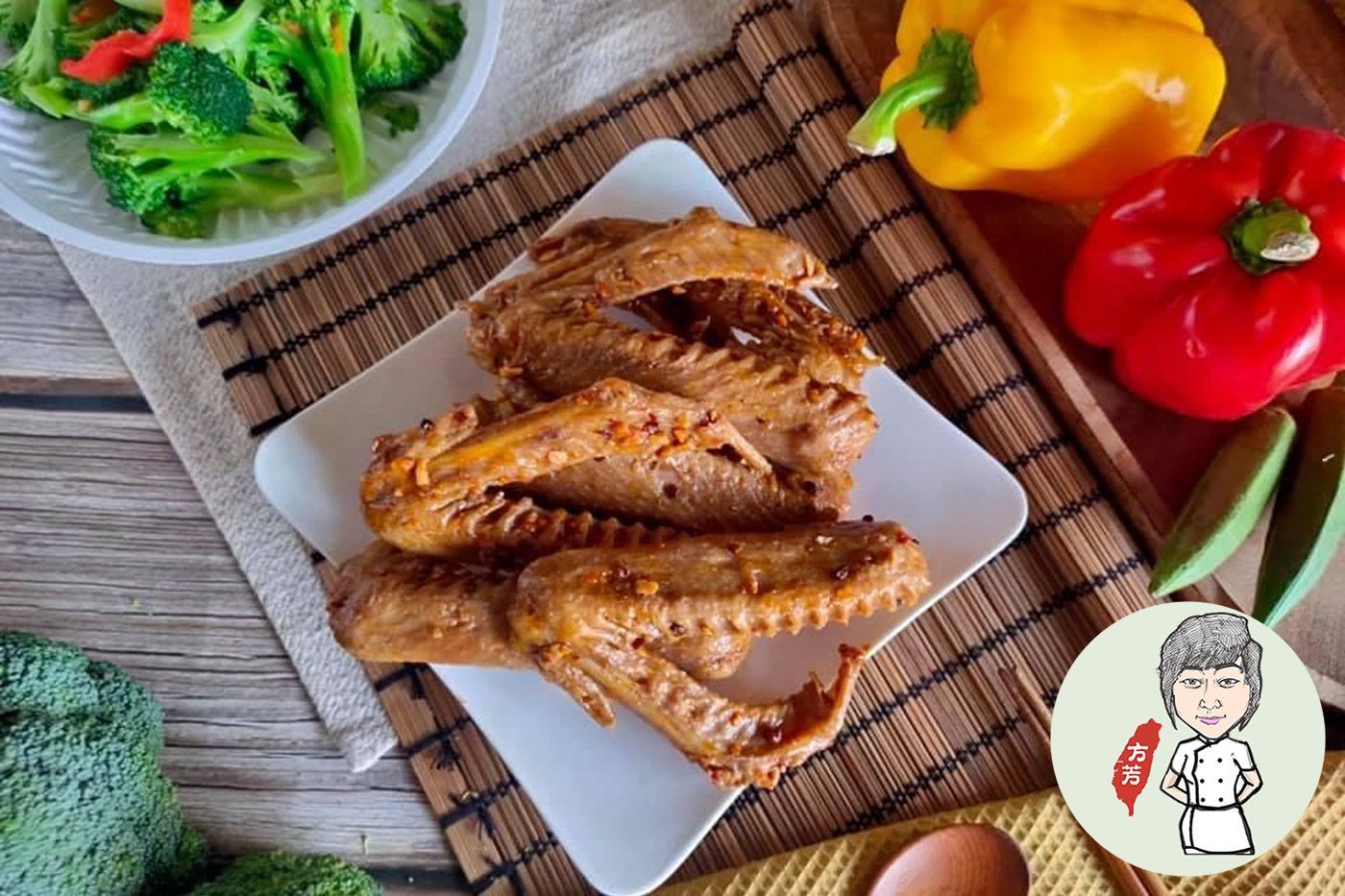 A white plate topped with chicken wings next to a bowl of broccoli and peppers.