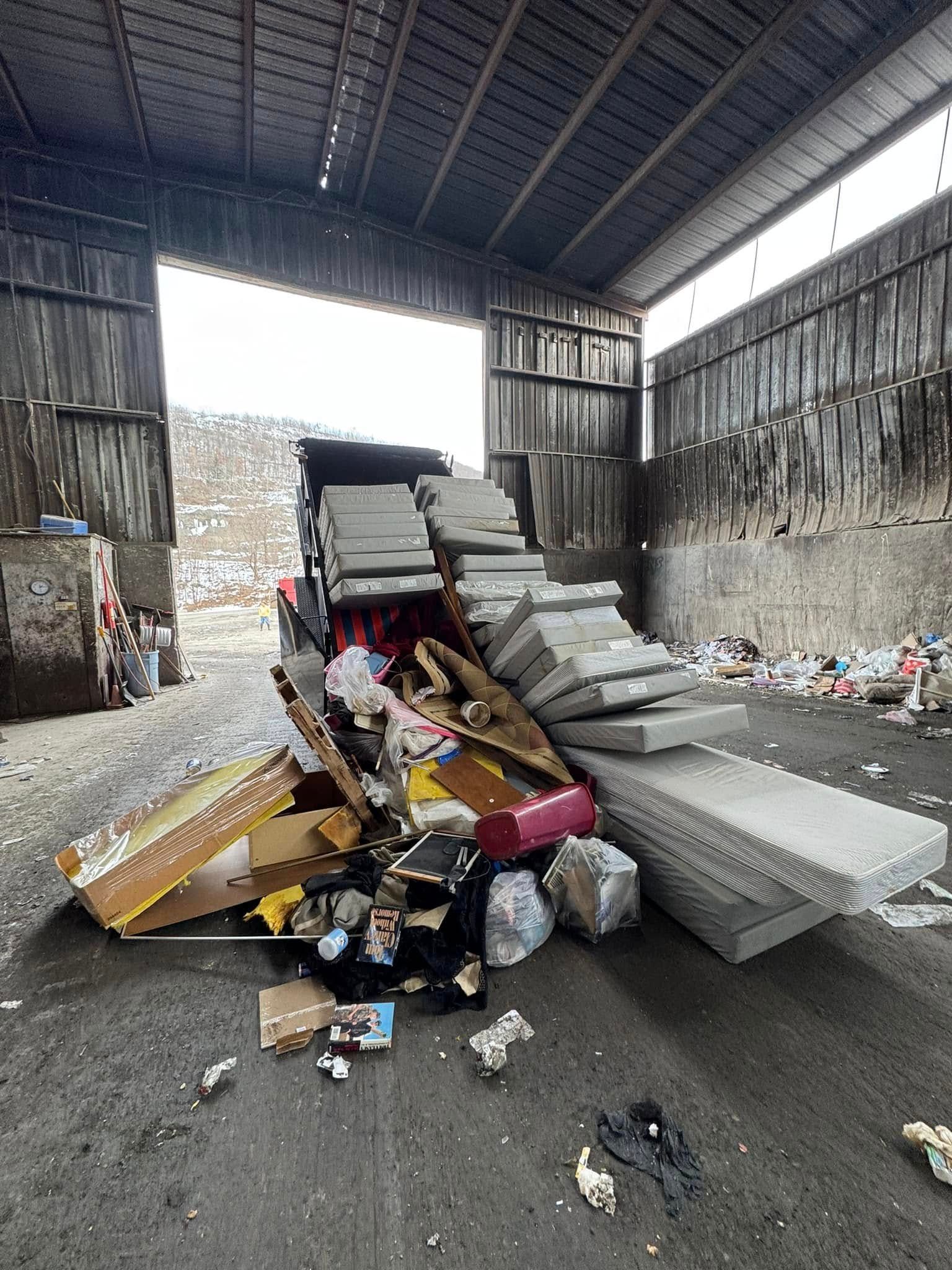 Pile of discarded items, including foam blocks, cardboard boxes, and trash, inside a warehouse.