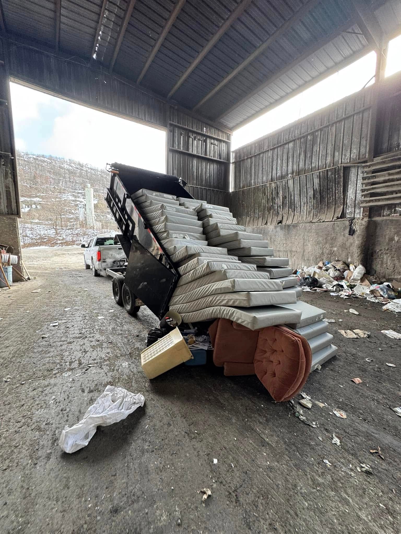 Dump truck unloading gray concrete blocks at a waste facility.