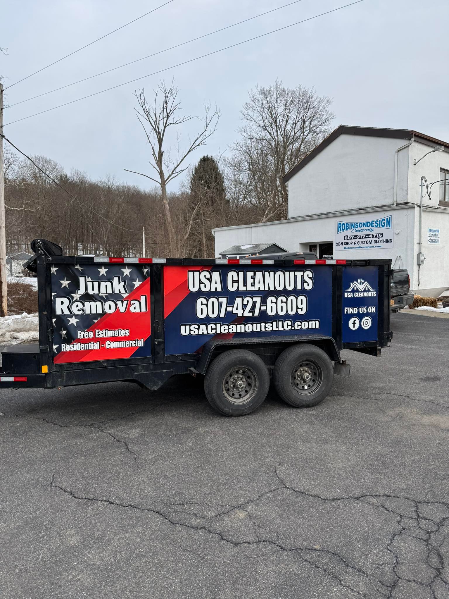USA Cleanouts trailer with junk removal logo, blue and red colors, parked on a street.