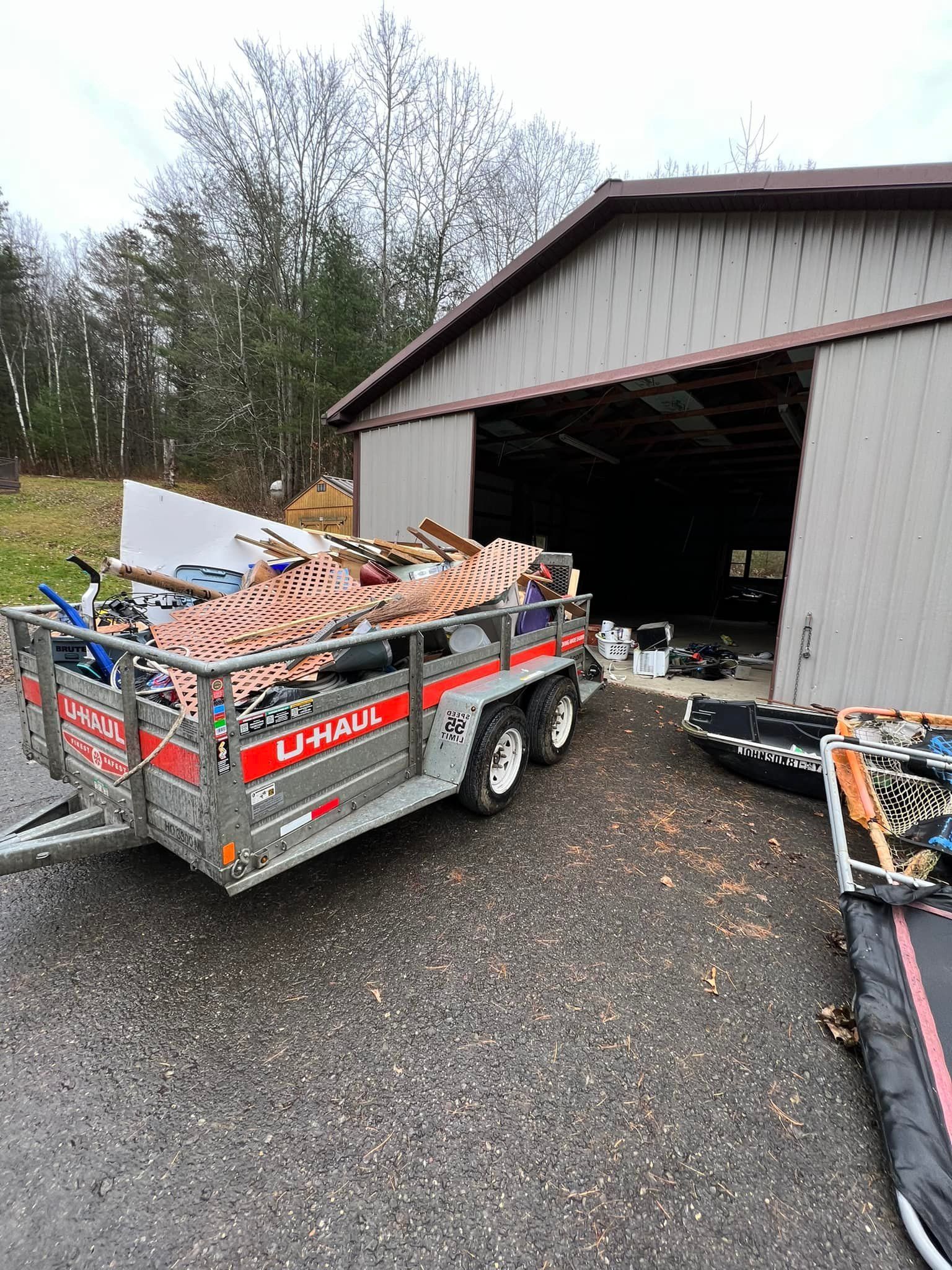 U-Haul trailer loaded with debris sits next to a large building with an open garage entrance.