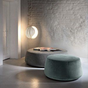 Due pouf sono posizionati uno accanto all'altro in una stanza con un muro di mattoni.