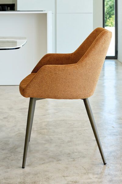 Una sedia marrone è appoggiata sul pavimento di cemento in una stanza.