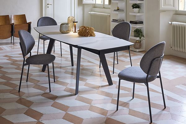 Una sala da pranzo con tavolo e sedie su pavimento piastrellato.