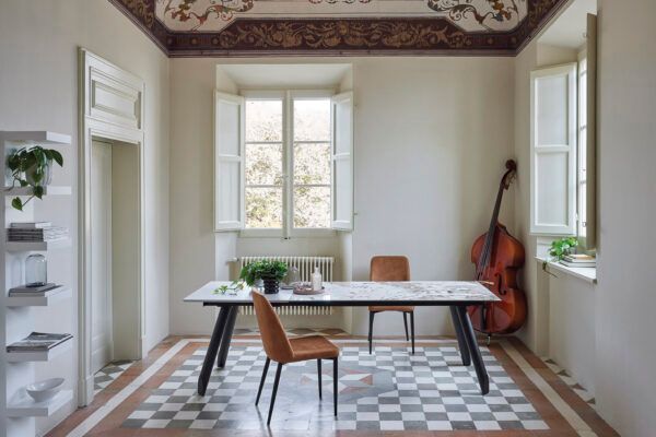 Una stanza con un tavolo, delle sedie e un violino sul muro.