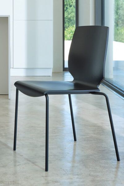 Una sedia nera è posta davanti a una finestra in una stanza.