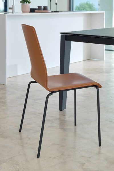 Una sedia marrone è appoggiata accanto a un tavolo nero in una cucina.