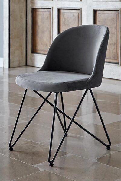 Una sedia grigia con le gambe nere è appoggiata su un pavimento piastrellato.