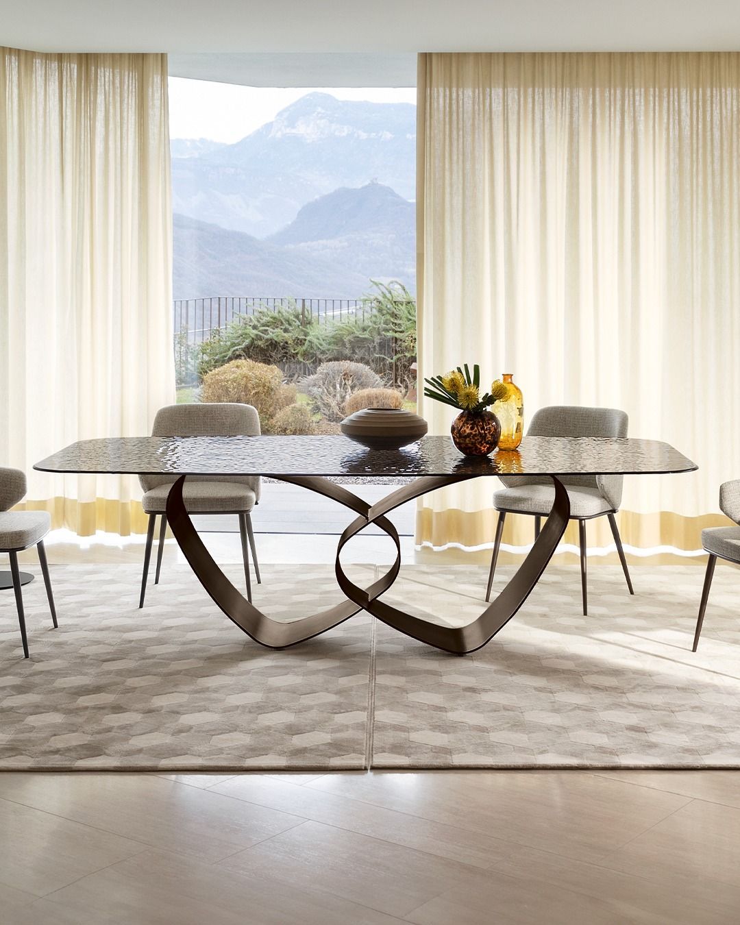 Un tavolo da pranzo con base a forma di cuore e sedie davanti a una finestra.