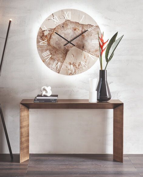 Un orologio con numeri romani è appeso sopra un tavolo di legno