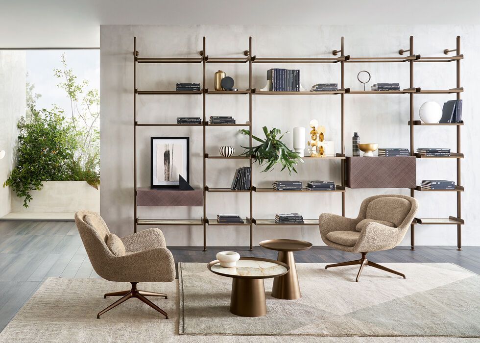 Un soggiorno con una libreria, sedie, tavoli e un tappeto.