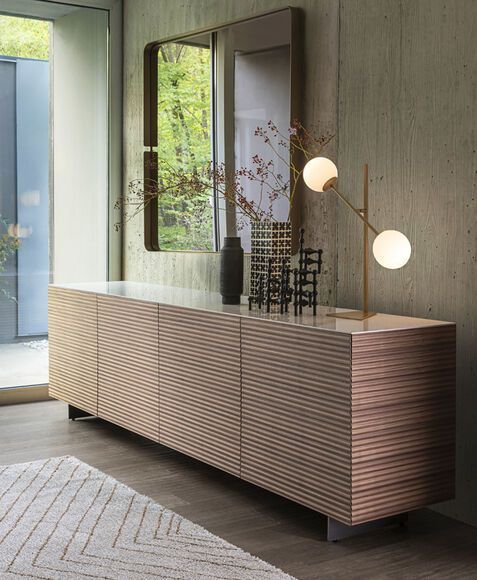 Una sala da pranzo con una lunga cassettiera in legno e uno specchio.