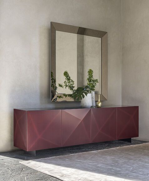 Un grande specchio è appeso alla parete sopra un mobile rosso.