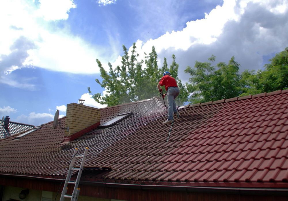 Professional Worker Cleaning a Roof Using Pressure Washing